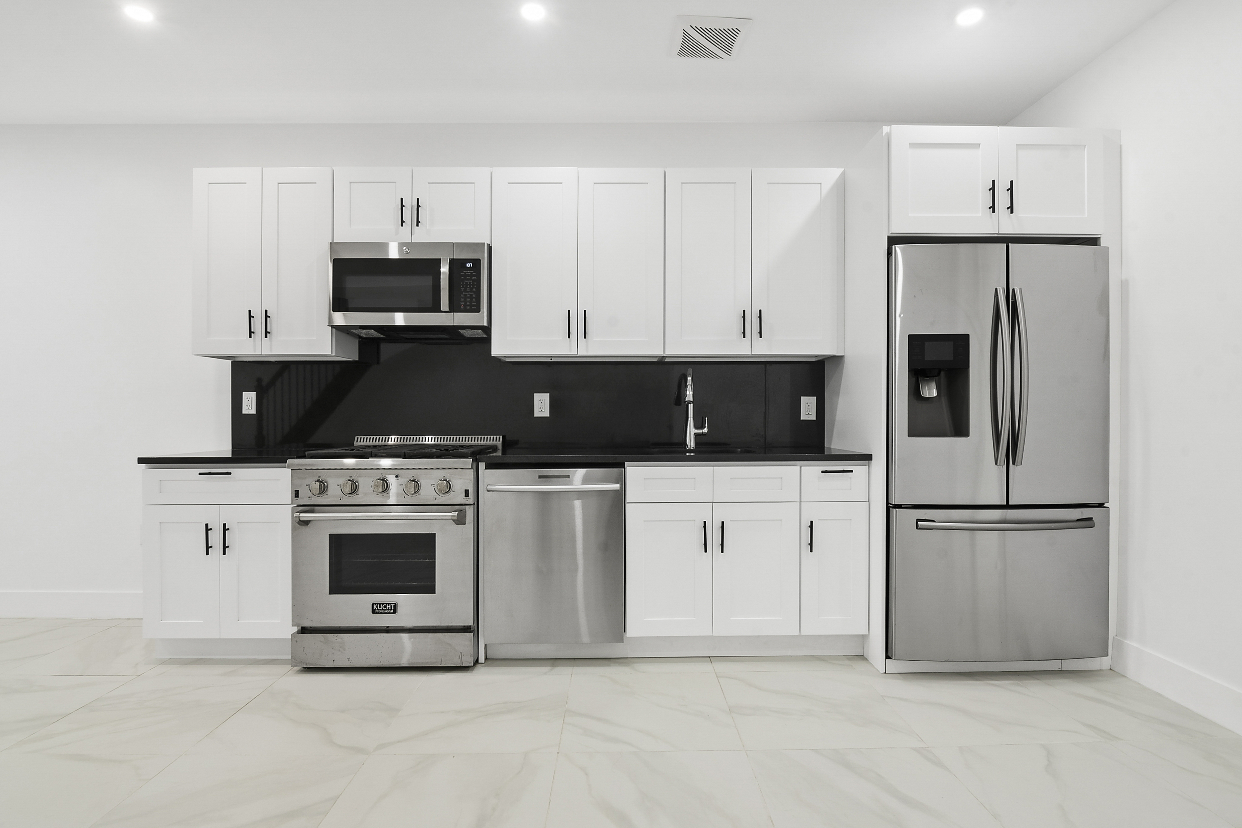1085 Hancock Street Brooklyn, NY 11221 - Photo 3 of 9 a kitchen with white cabinets and stainless steel appliances