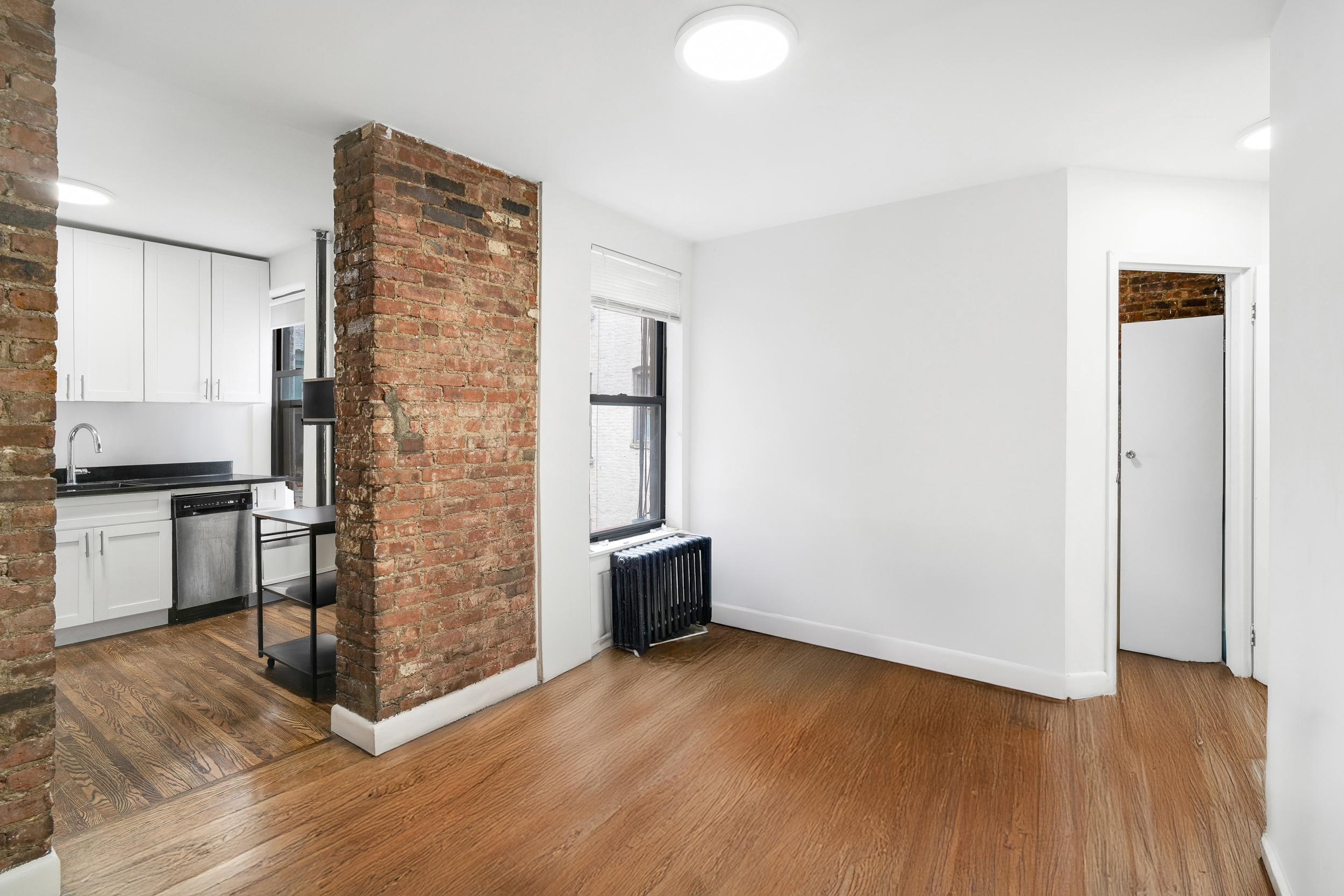 214 East 82nd Street, Unit 27 Manhattan, NY 10028 - Photo 2 of 6 a view of empty room with wooden floor and kitchen