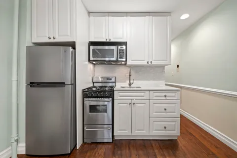 a kitchen with white cabinets and stainless steel appliances