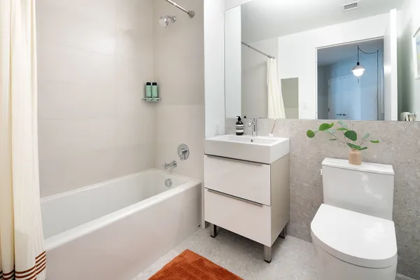 a white toilet sitting next to a bathroom sink and tub