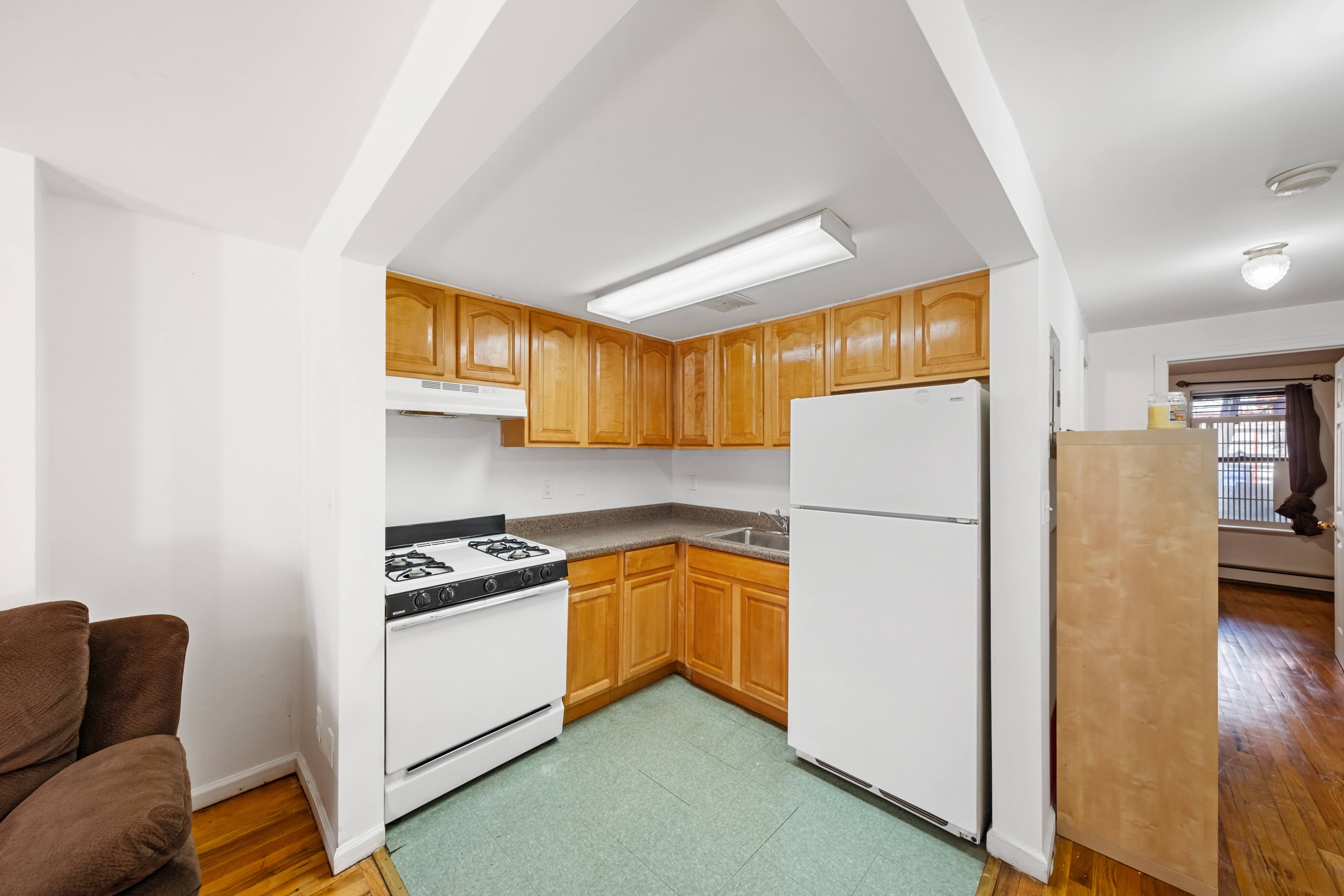 275 Van Buren Street Brooklyn, NY 11221 - Photo 17 of 33 a kitchen with a refrigerator a stove top oven a counter space and wooden floor