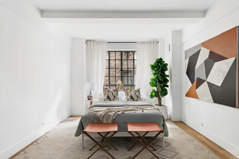 a bed sitting in a bedroom next to a window and a potted plant