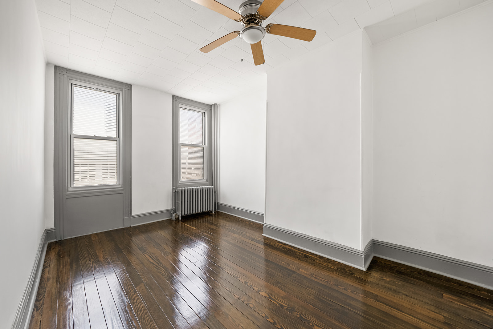 59-45 Palmetto Street Queens, NY 11385 - Photo 3 of 25 an empty room with wooden floor chandelier fan and windows