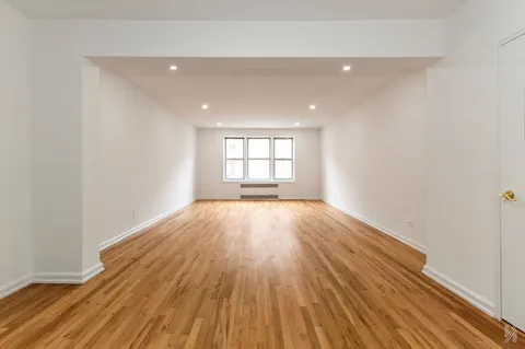 an empty room with wooden floor and window