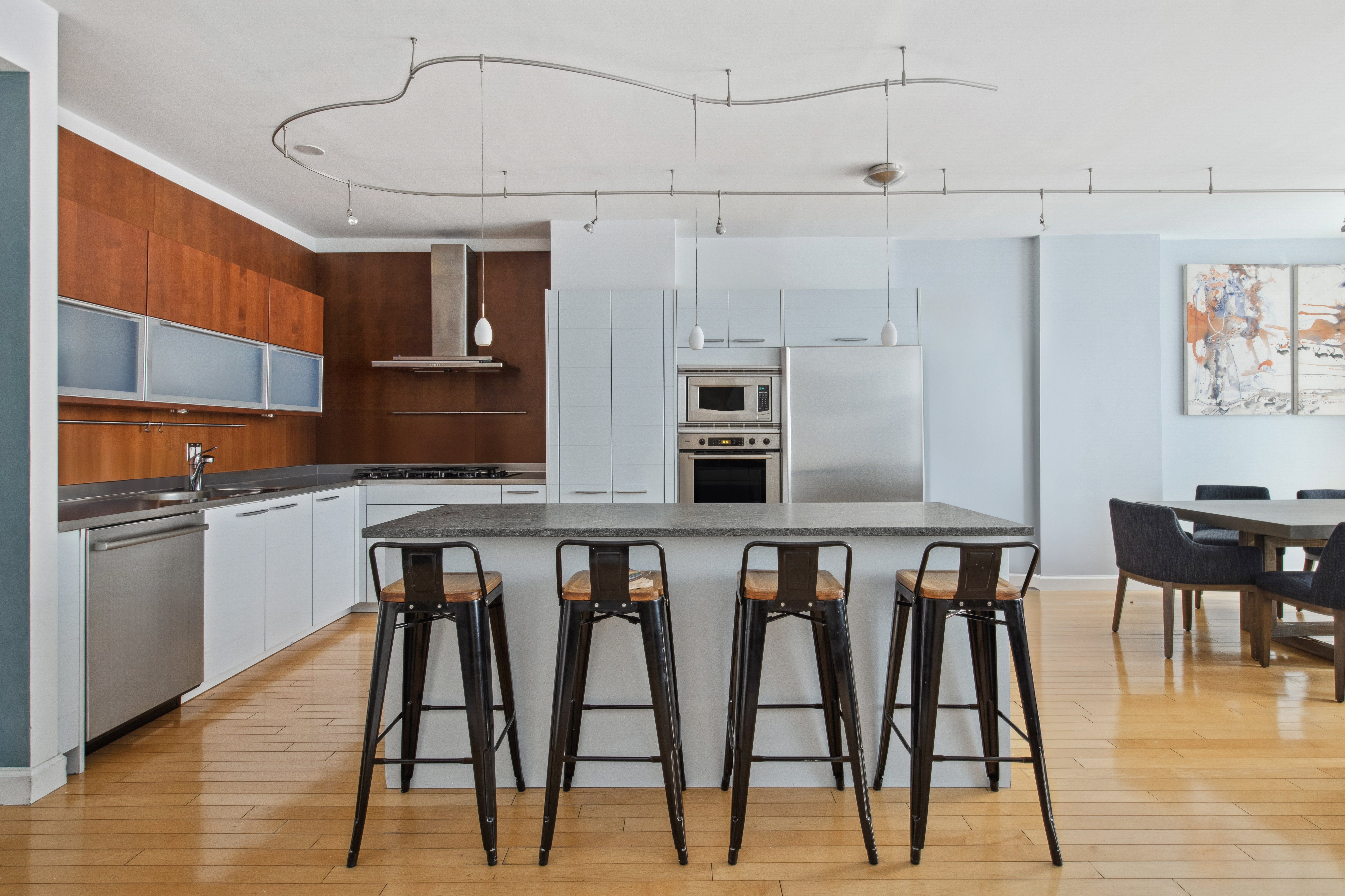 151 West 17th Street, Unit 5A Manhattan, NY 10011 - Photo 6 of 11 a dining room with stainless steel appliances kitchen island granite countertop a table chairs and a refrigerator