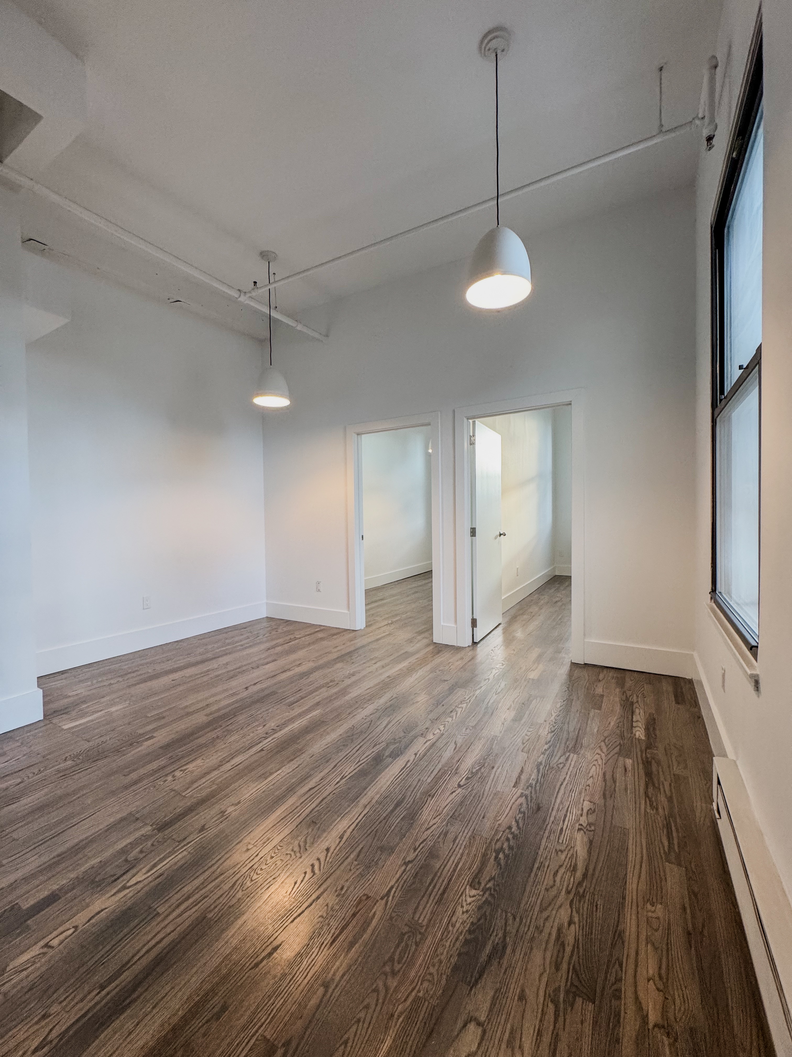 44 Berry Street, Unit 4J Brooklyn, NY 11249 - Photo 3 of 8 a view of an empty room with wooden floor and a window