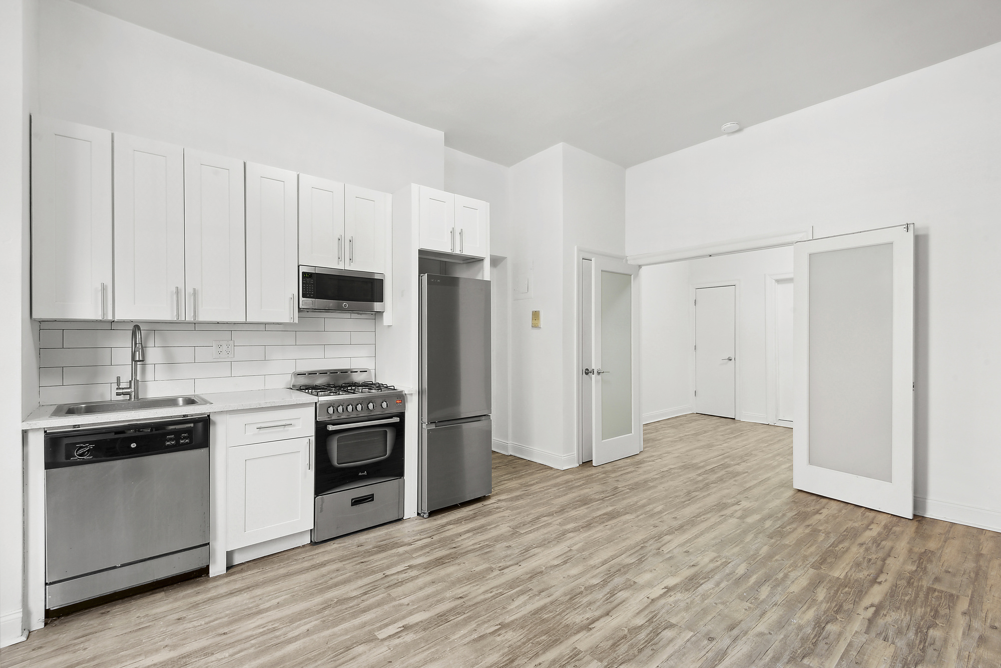 164 West 128th Street, Unit 1A Manhattan, NY 10027 - Photo 2 of 5 a kitchen with stainless steel appliances white cabinets and a refrigerator
