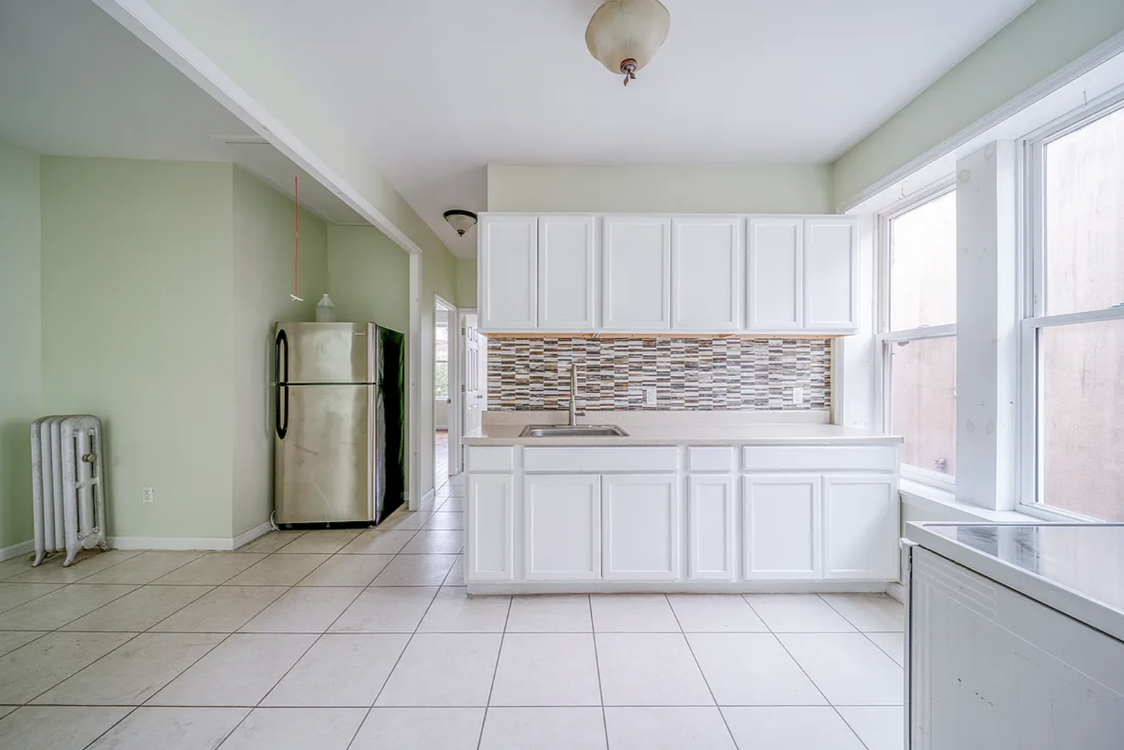 96 East 32nd Street, Unit 2 Brooklyn, NY 11226 - Photo 2 of 6 a kitchen with white cabinets and refrigerator