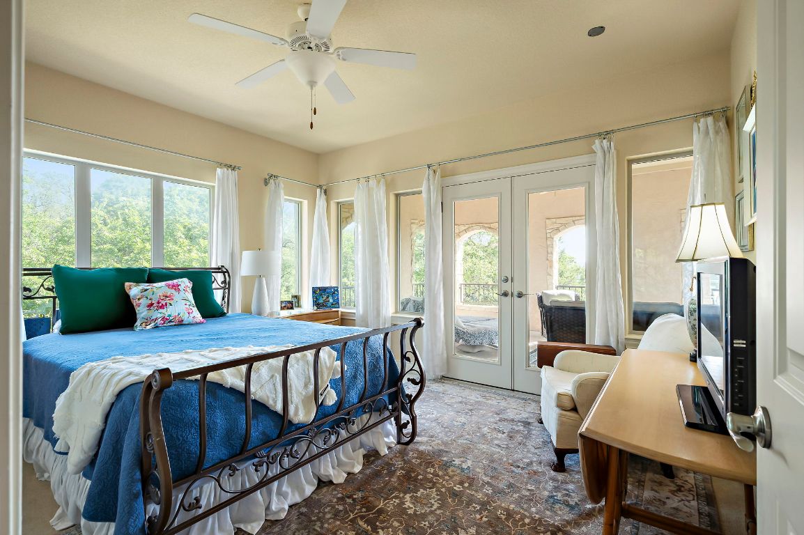 1607 The High Road Austin, TX 78746 - Photo 22 of 28 a bedroom with a bed a table and large windows