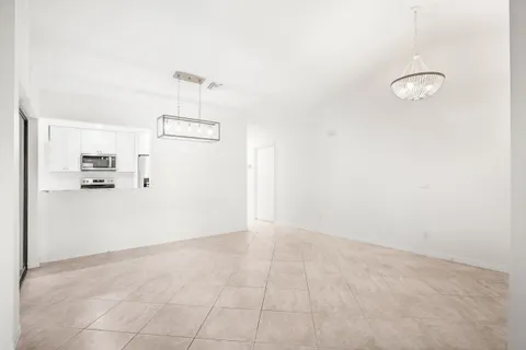 an empty room with kitchen view and refrigerator