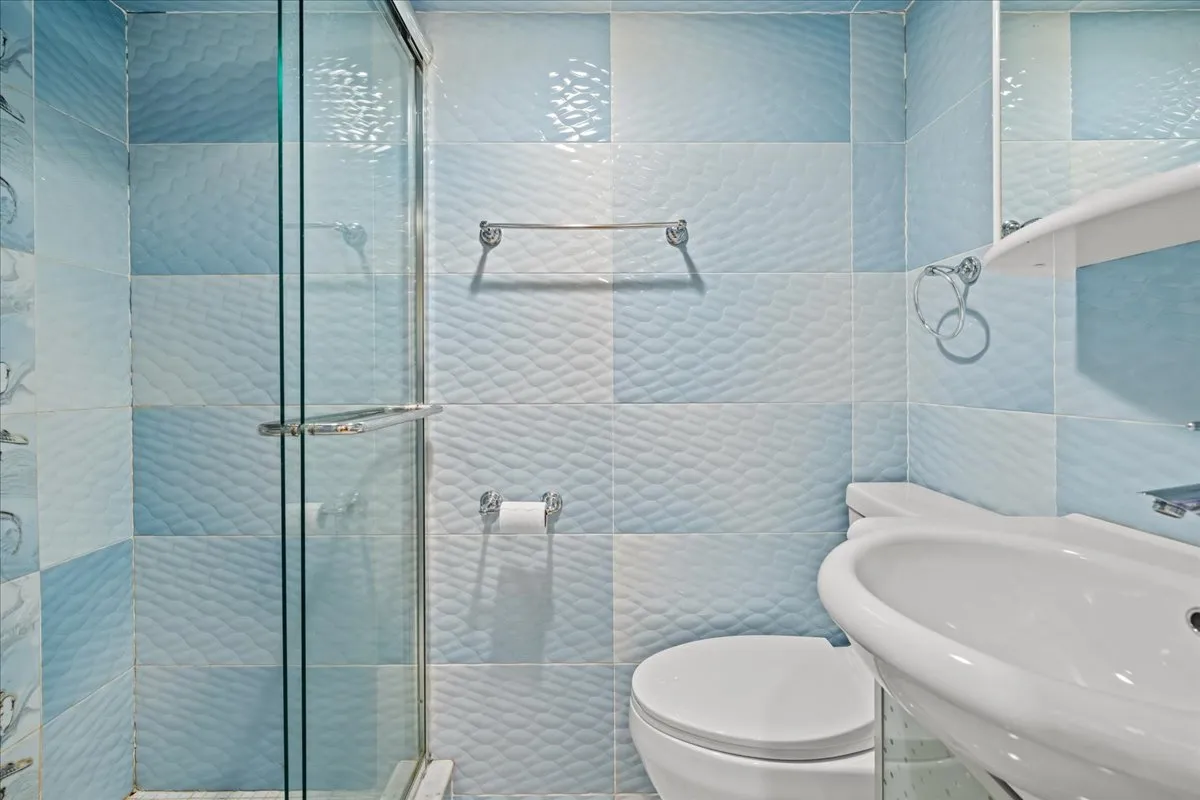 a white toilet sitting next to a bathroom sink and a shower