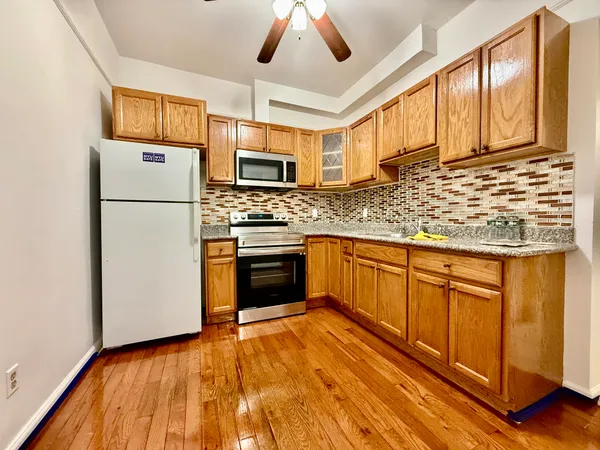 a kitchen with stainless steel appliances granite countertop a refrigerator a stove top oven a sink and dishwasher with wooden floor