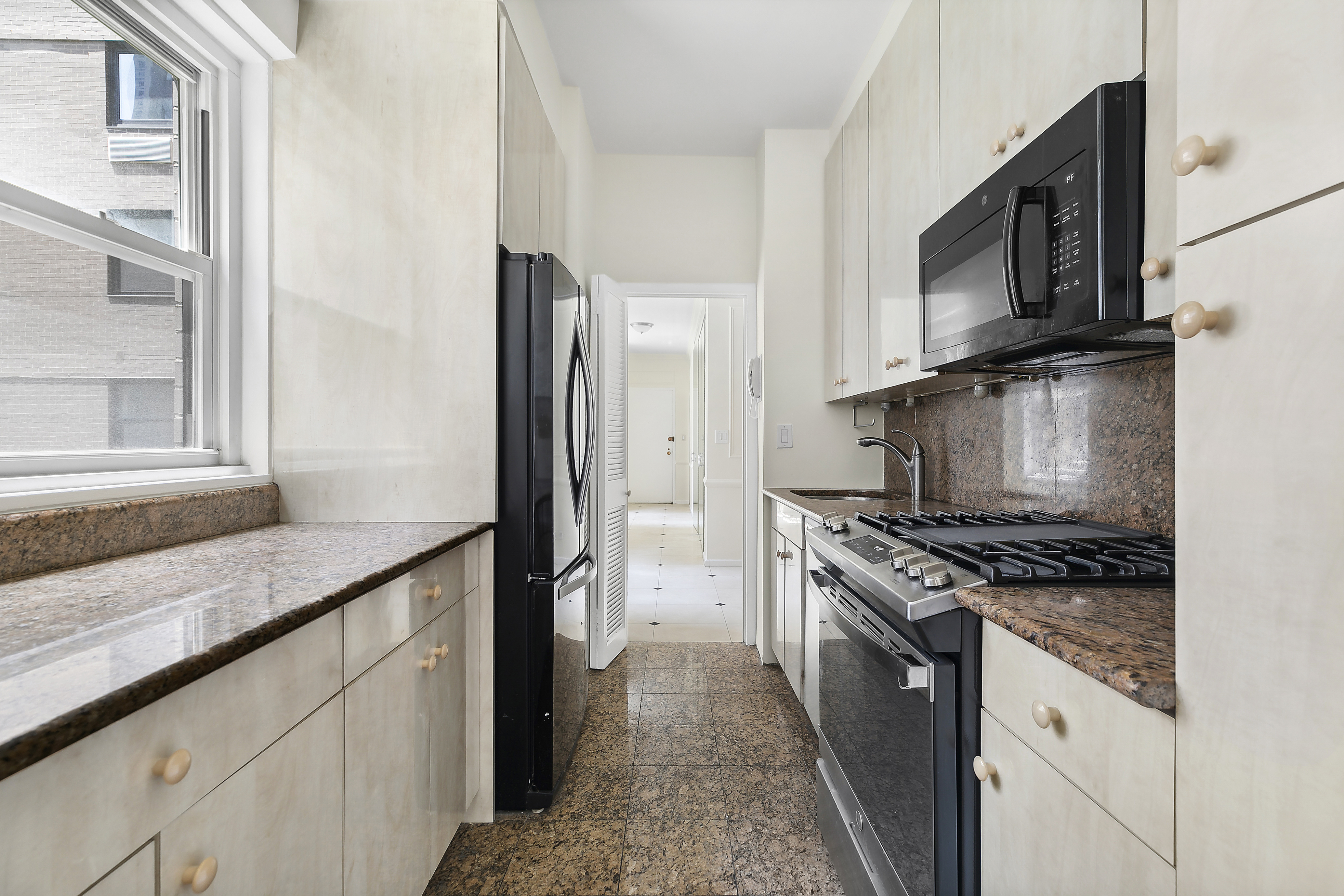 58 West 58th Street, Unit 4C Manhattan, NY 10019 - Photo 3 of 14 a kitchen with stainless steel appliances granite countertop a stove and a microwave
