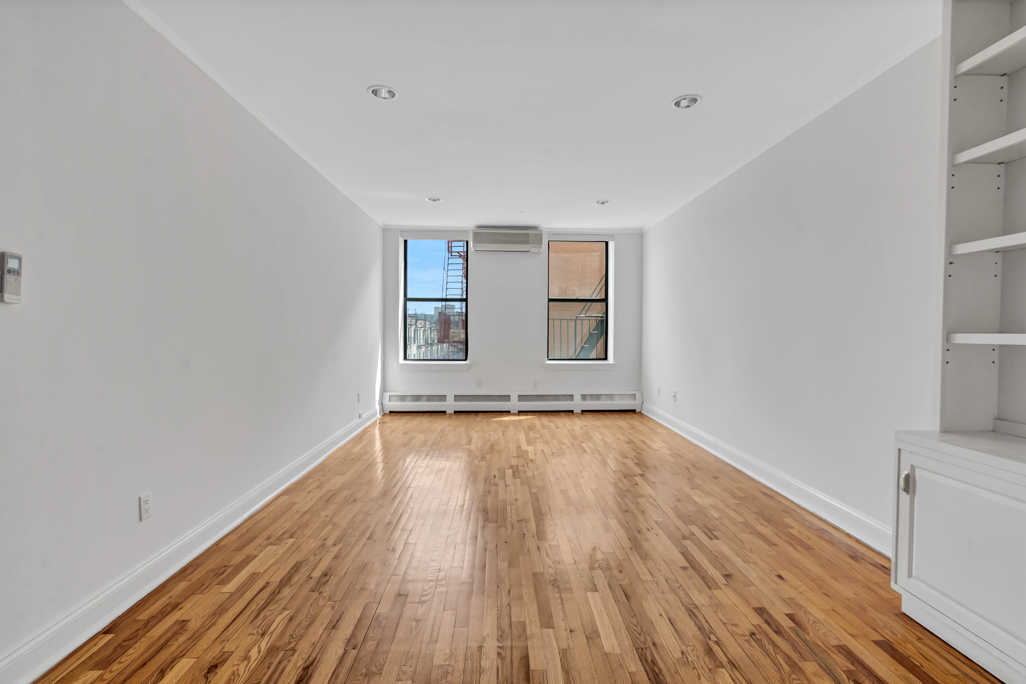 2098 Frederick Douglass Boulevard, Unit 5E Manhattan, NY 10026 - Photo 2 of 8 a view of empty room with wooden floor and fan