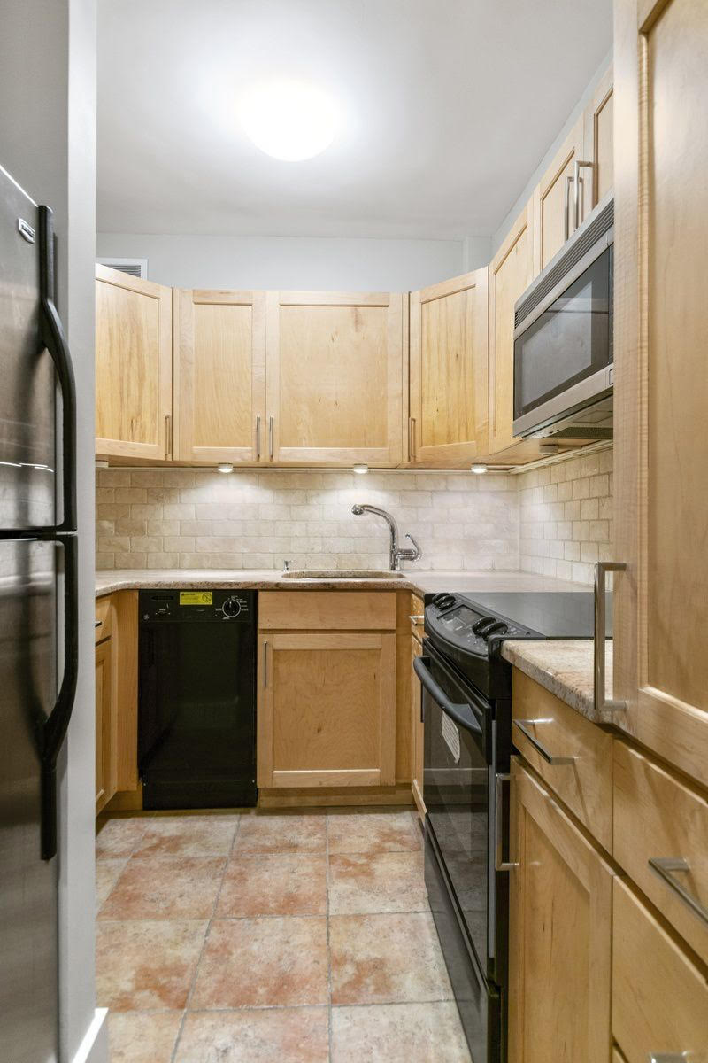 80 Park Avenue, Unit 9L Manhattan, NY 10016 - Photo 5 of 10 a kitchen with stainless steel appliances granite countertop a stove a sink and a microwave