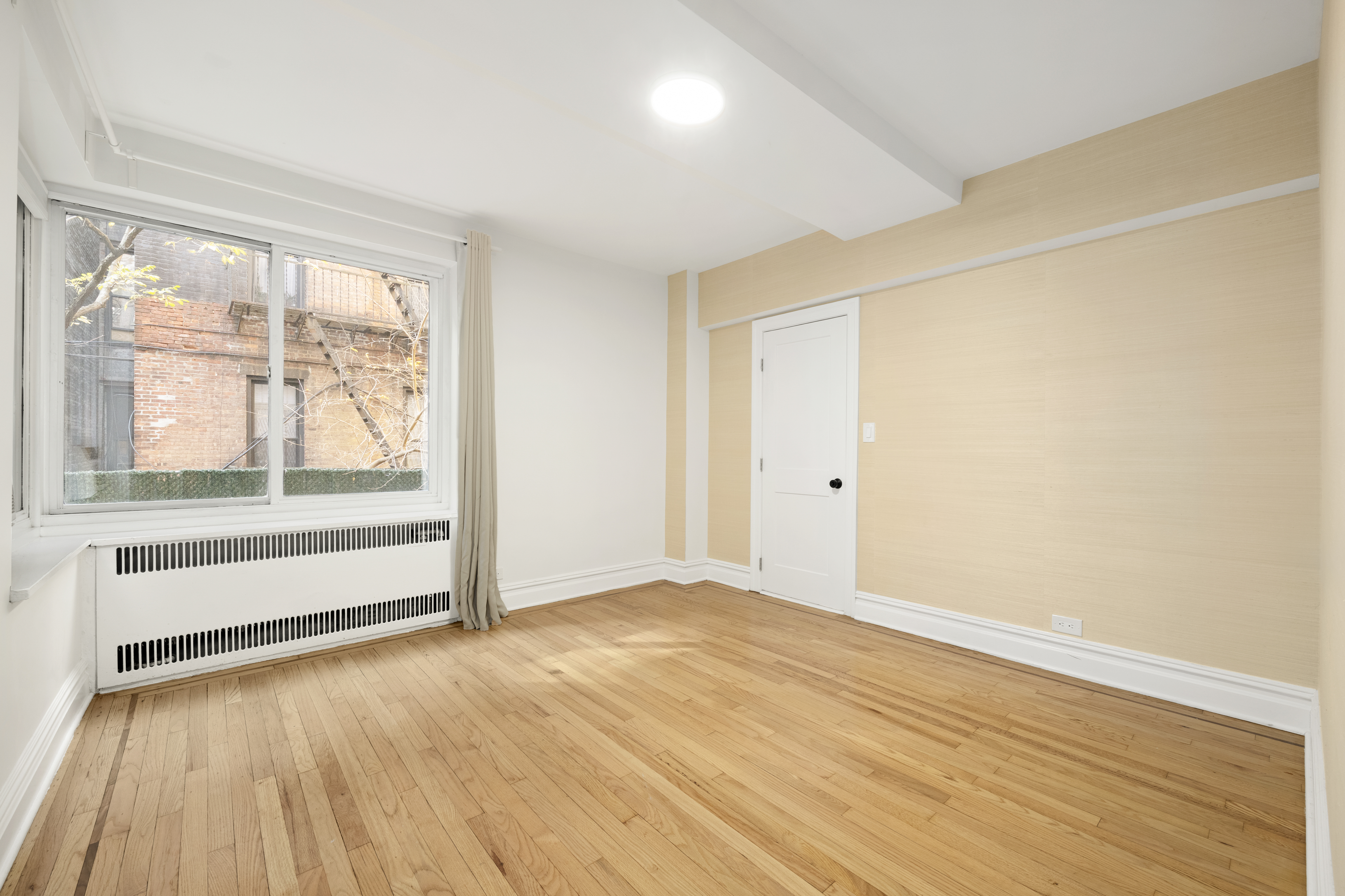 152 East 94th Street, Unit 2J Manhattan, NY 10128 - Photo 12 of 18 an empty room with wooden floor and windows