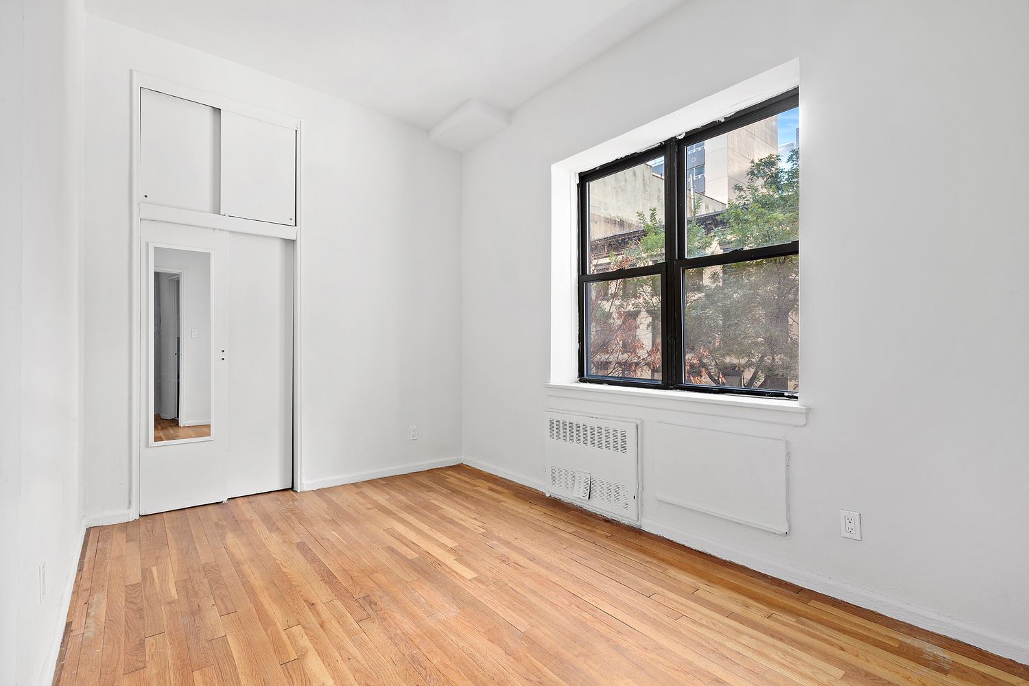 301 East 49th Street, Unit 3AB Manhattan, NY 10017 - Photo 2 of 7 an empty room with wooden floor and windows