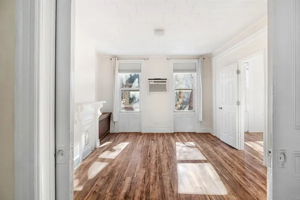 a view of a hallway with wooden floor and a living room