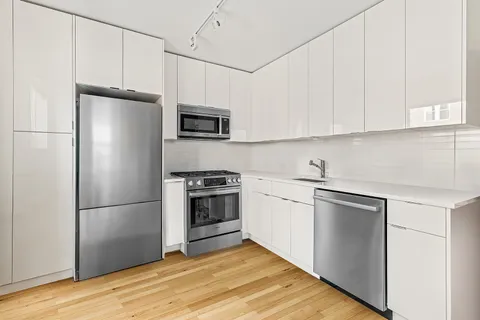 a kitchen with cabinets stainless steel appliances and wooden floor