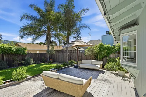 a view of a patio with couches table and chairs with wooden fence and plants