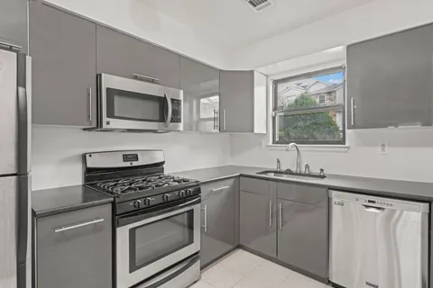 a kitchen with cabinets stainless steel appliances a sink and a window