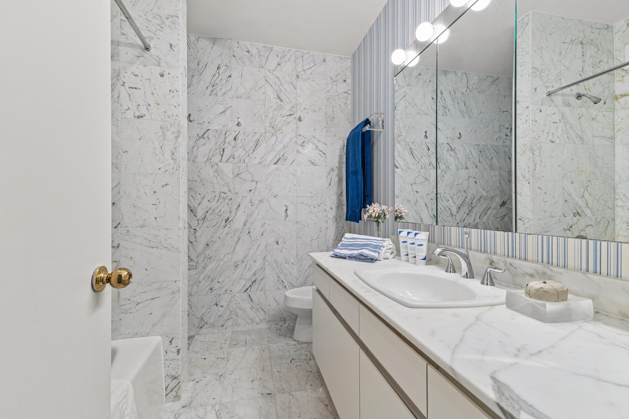 167 East 61st Street, Unit 20E Manhattan, NY 10065 - Photo 11 of 24 a bathroom with a granite countertop sink a mirror and shower