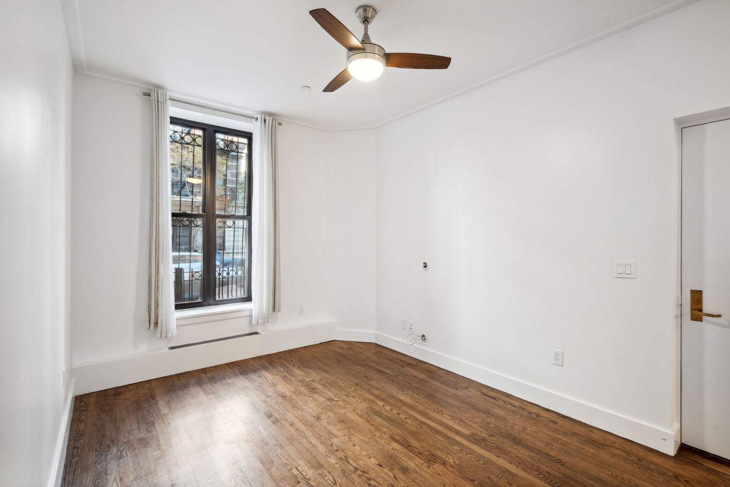 an empty room with wooden floor fan and windows