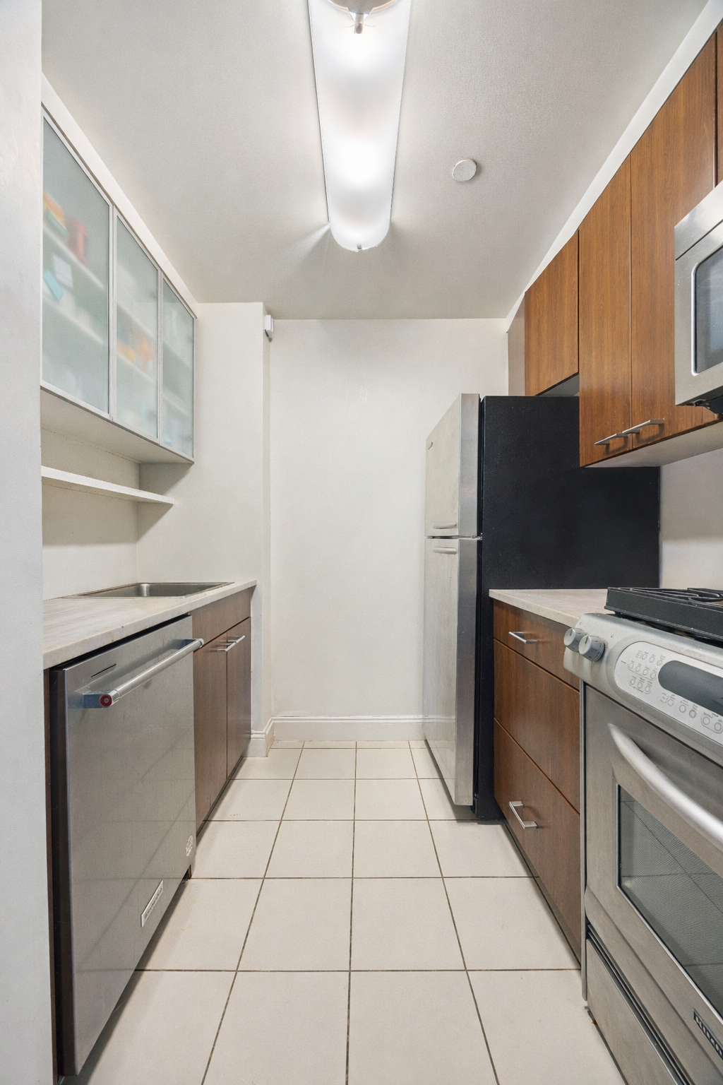 215-217 East 96th Street, Unit 26F Manhattan, NY 10128 - Photo 3 of 19 a kitchen with a stove top oven and cabinets