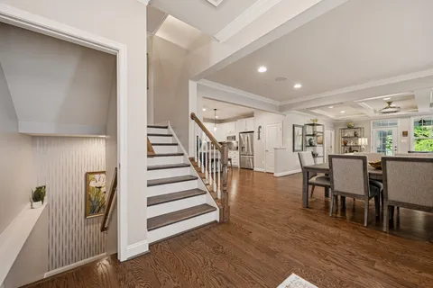 a kitchen with stainless steel appliances granite countertop a stove a refrigerator a microwave oven a dining table and chairs with wooden floor