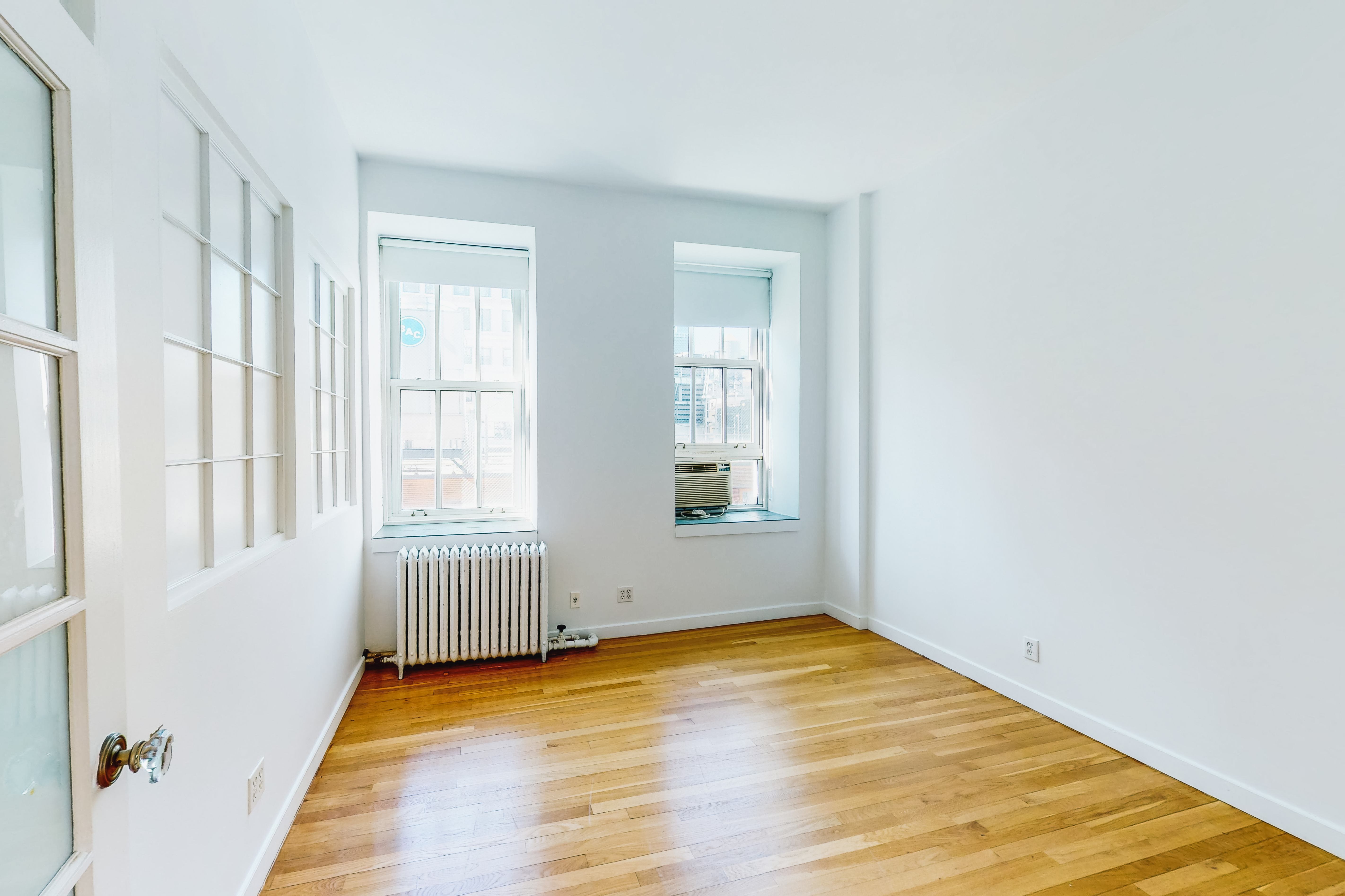 395 Broadway, Unit 7E Manhattan, NY 10013 - Photo 6 of 7 a view of an empty room with wooden floor and a window