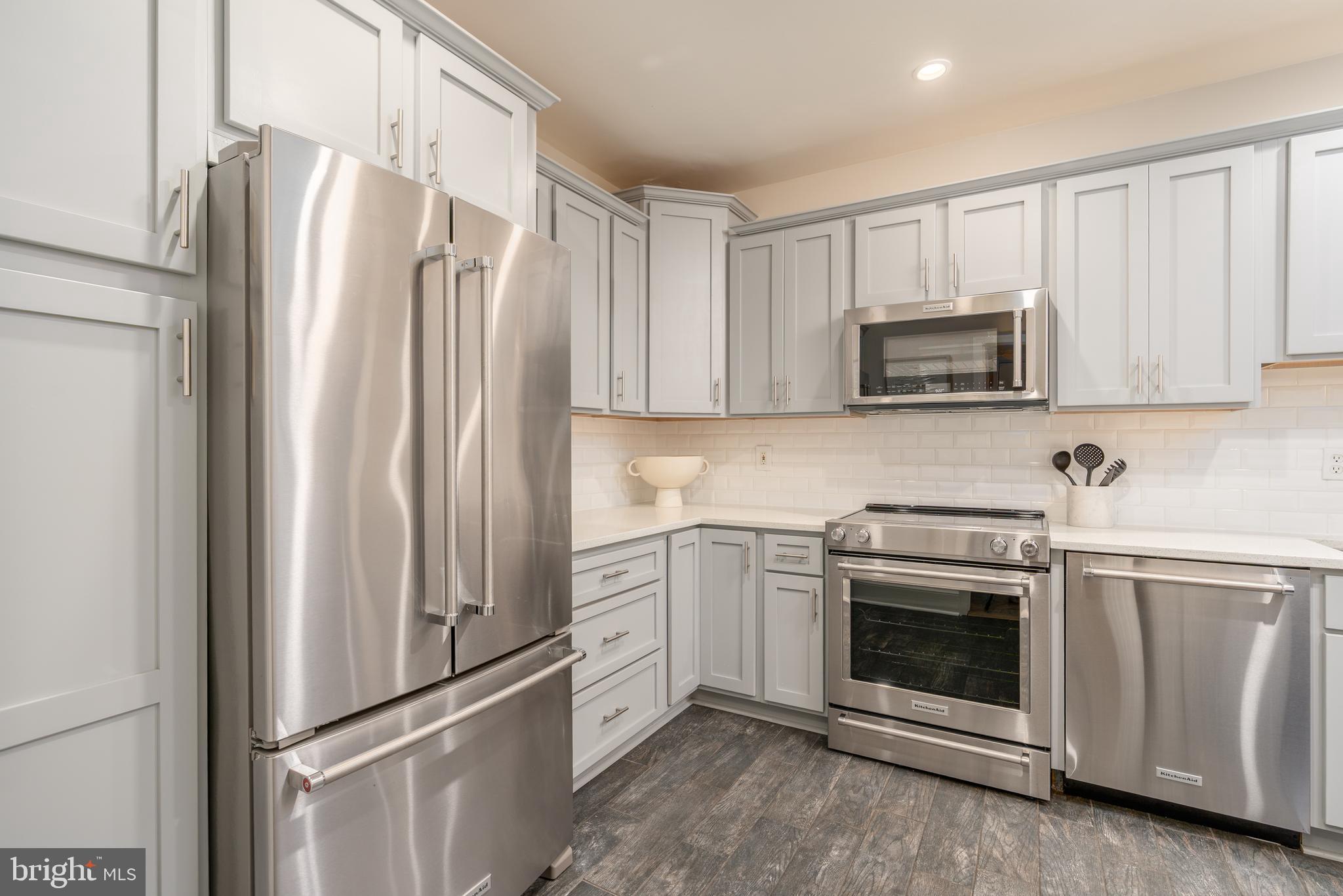 3299 Sutton Place Northwest, Unit C Washington, DC 20016 - Photo 17 of 41 a kitchen with stainless steel appliances white cabinets white stove a microwave and a refrigerator