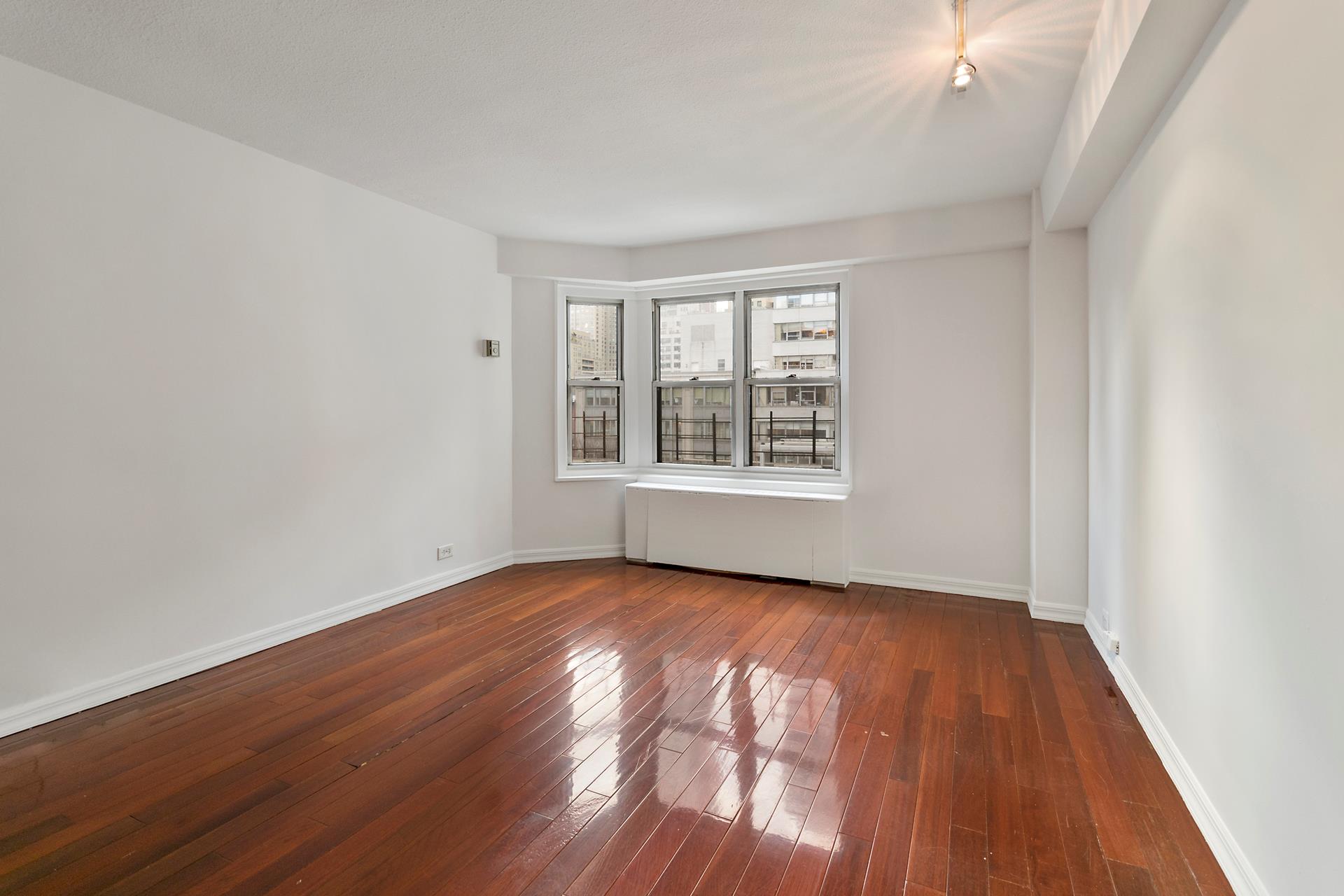 220 East 60th Street, Unit 7CD Manhattan, NY 10022 - Photo 4 of 11 a view of an empty room with wooden floor and a window