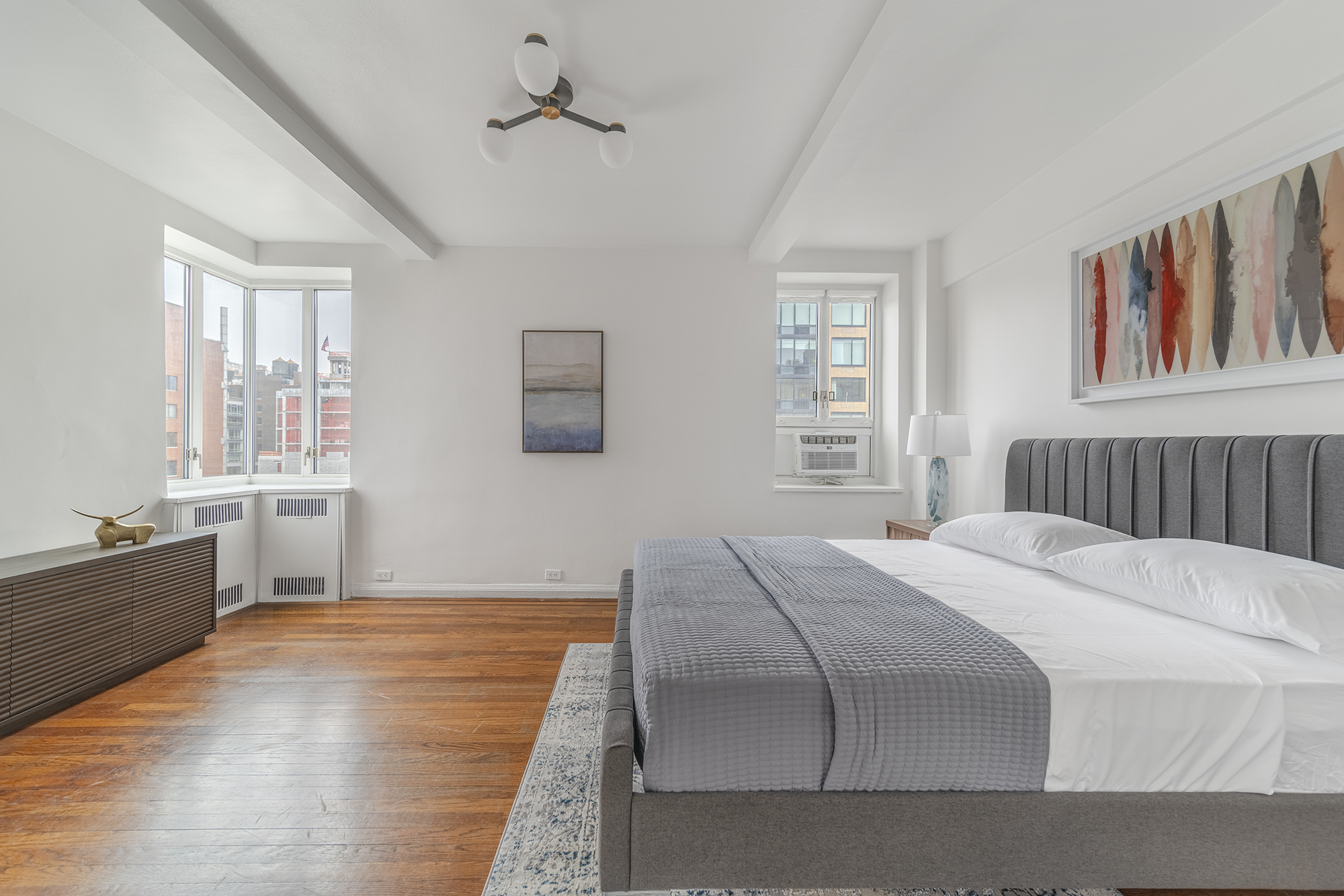 200 West 20th Street, Unit 1208 Manhattan, NY 10011 - Photo 8 of 14 a bedroom with a large bed a chandelier and windows