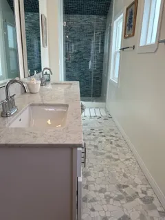 a bathroom with a granite countertop sink a mirror and a shower