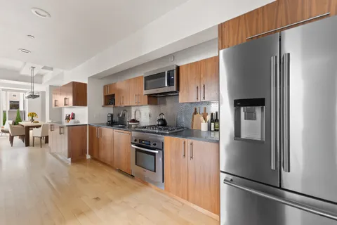 a kitchen with stainless steel appliances granite countertop a refrigerator a stove and a sink