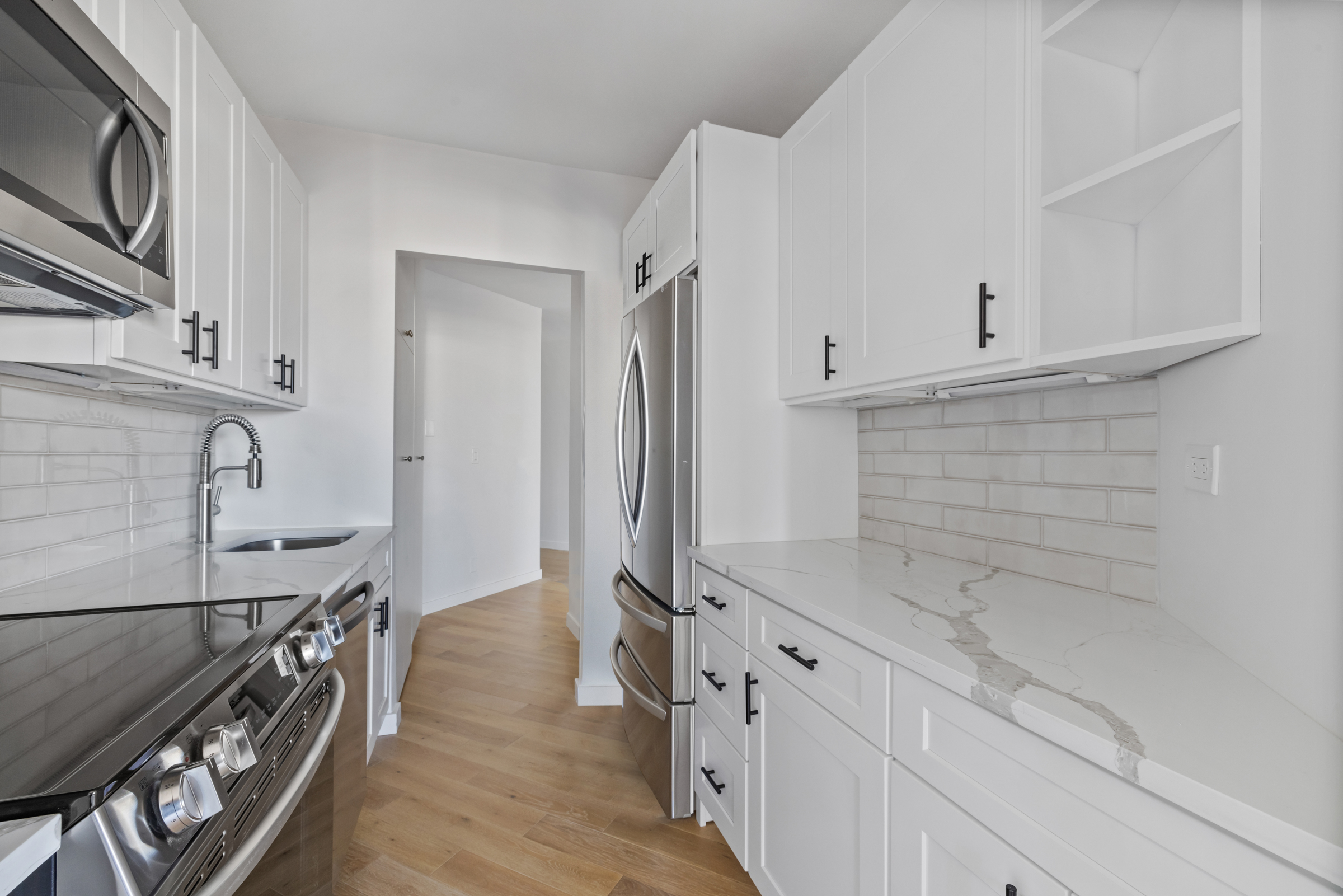 240 East 47th Street, Unit 27C Manhattan, NY 10017 - Photo 3 of 11 a kitchen with stainless steel appliances white cabinets and a window