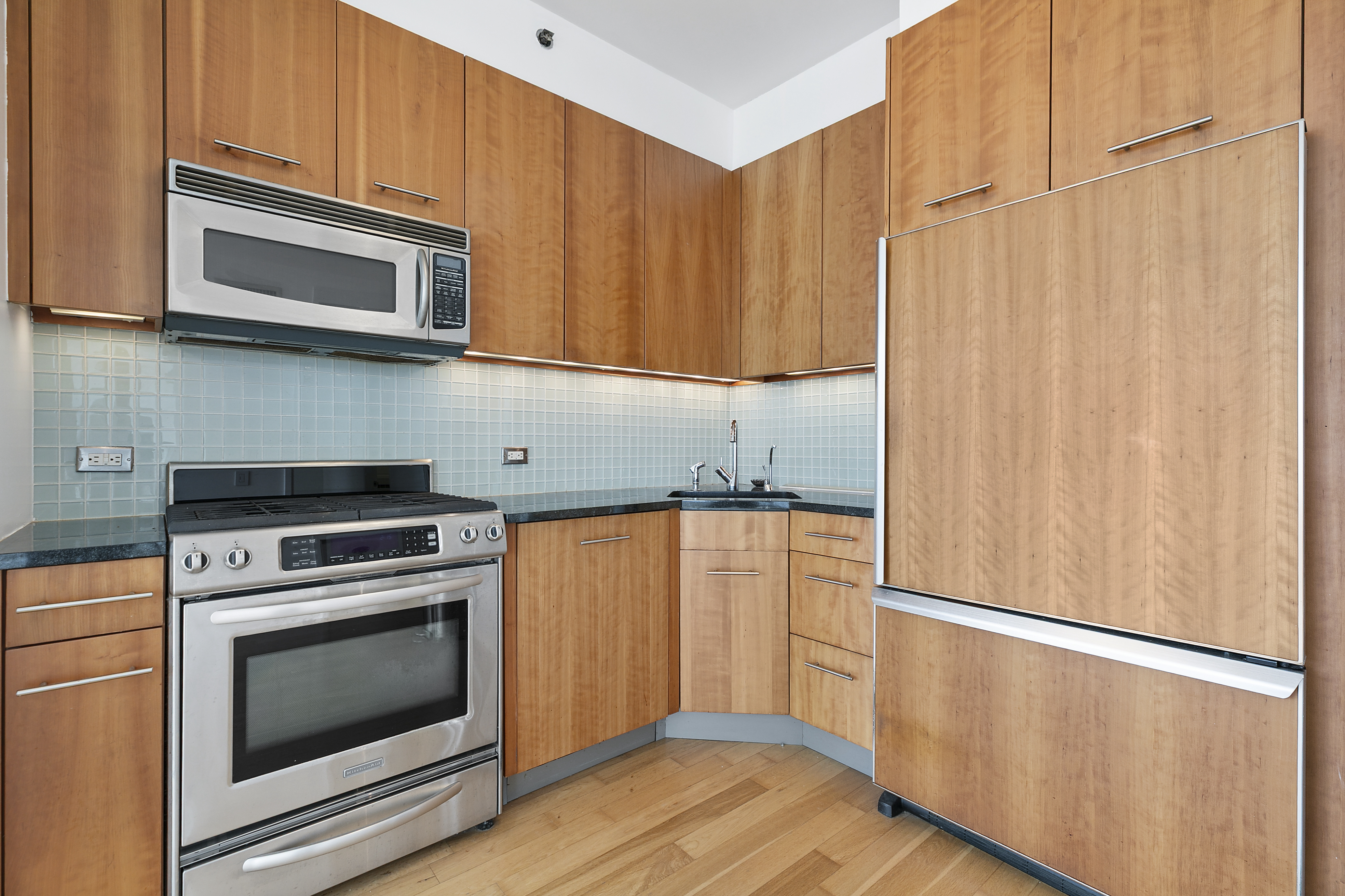 11 East 29th Street, Unit 44C Manhattan, NY 10016 - Photo 5 of 8 a kitchen with granite countertop a refrigerator stove and microwave