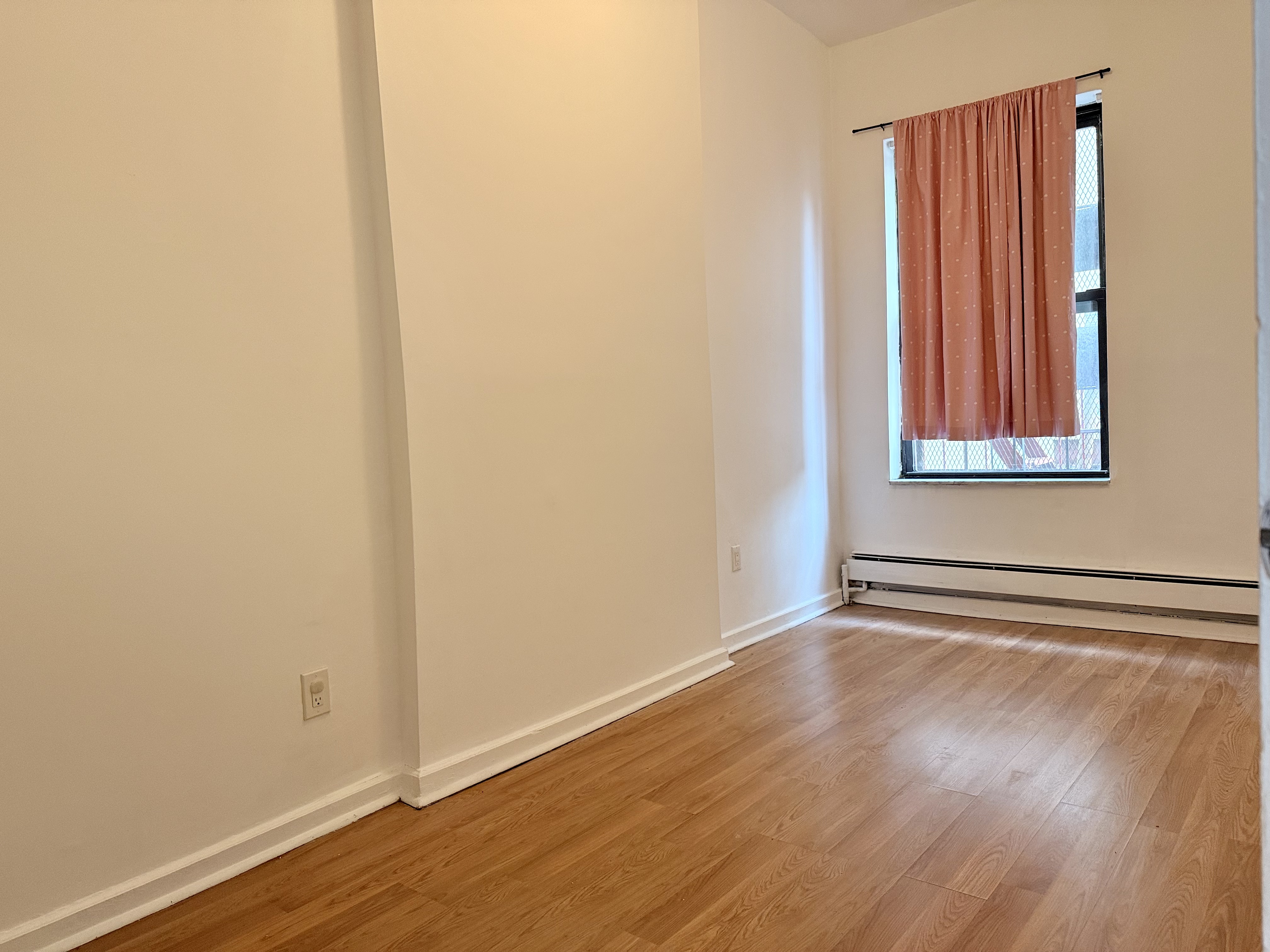 1997 3rd Avenue, Unit 1A Manhattan, NY 10029 - Photo 15 of 23 a view of an empty room with wooden floor and a window