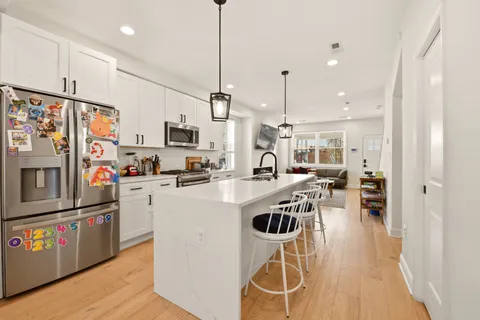 a kitchen with stainless steel appliances a stove a refrigerator a kitchen island a sink and a refrigerator