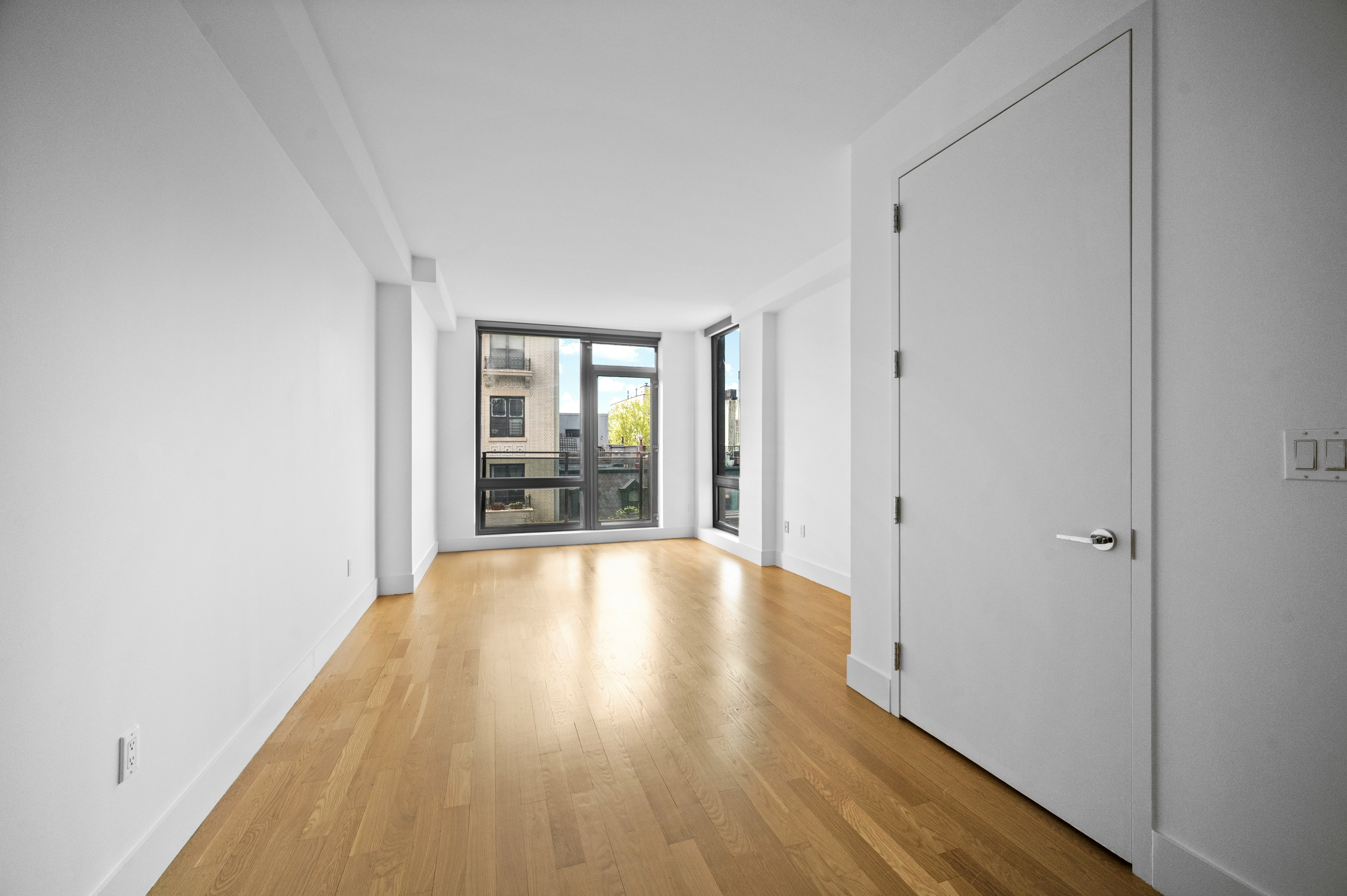 117 West 123rd Street, Unit 5D Manhattan, NY 10027 - Photo 7 of 18 a view of an empty room with wooden floor and a window