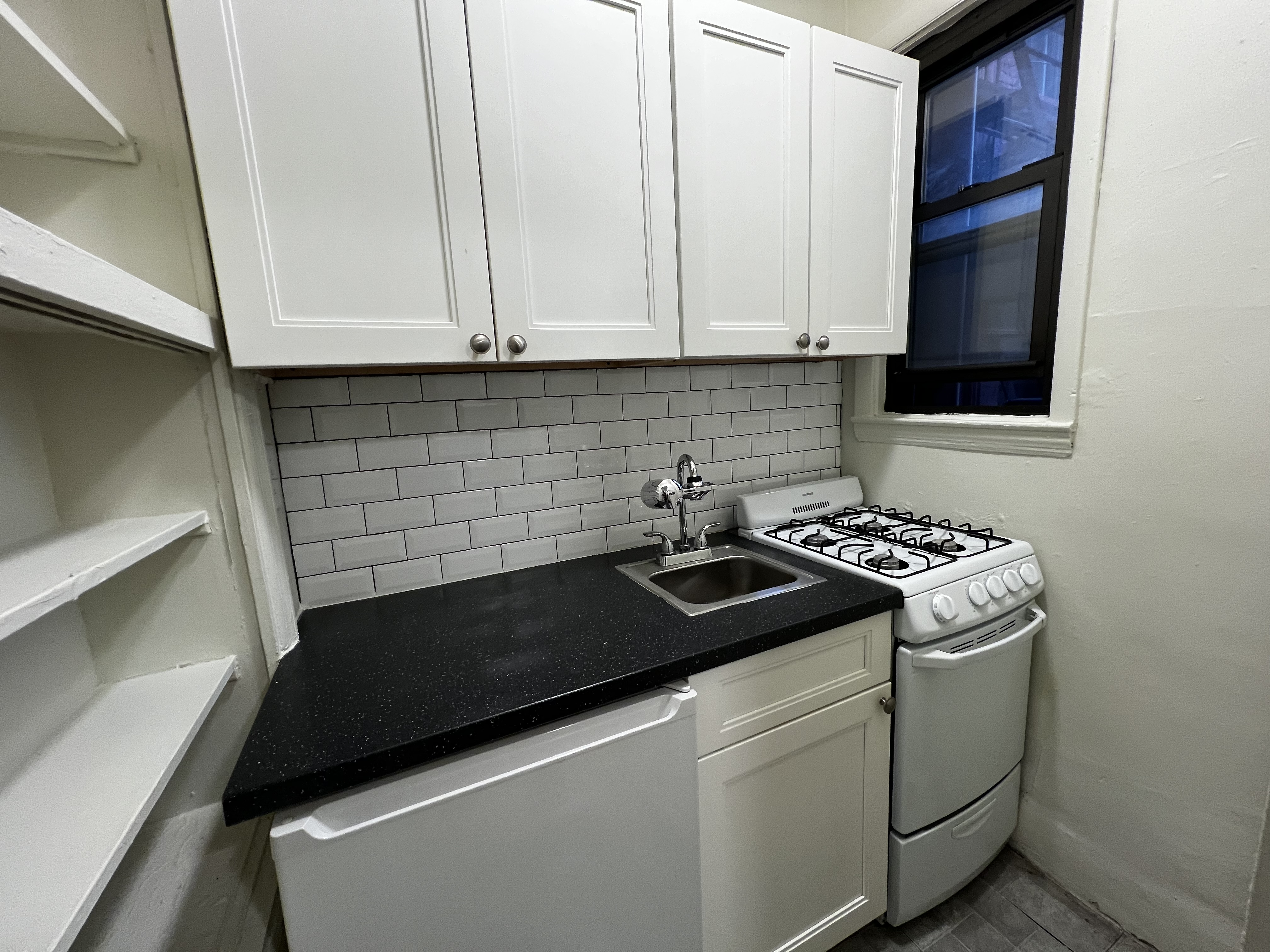 151 East 43rd Street, Unit 4B Manhattan, NY 10017 - Photo 4 of 7 a kitchen with granite countertop cabinets and white appliances