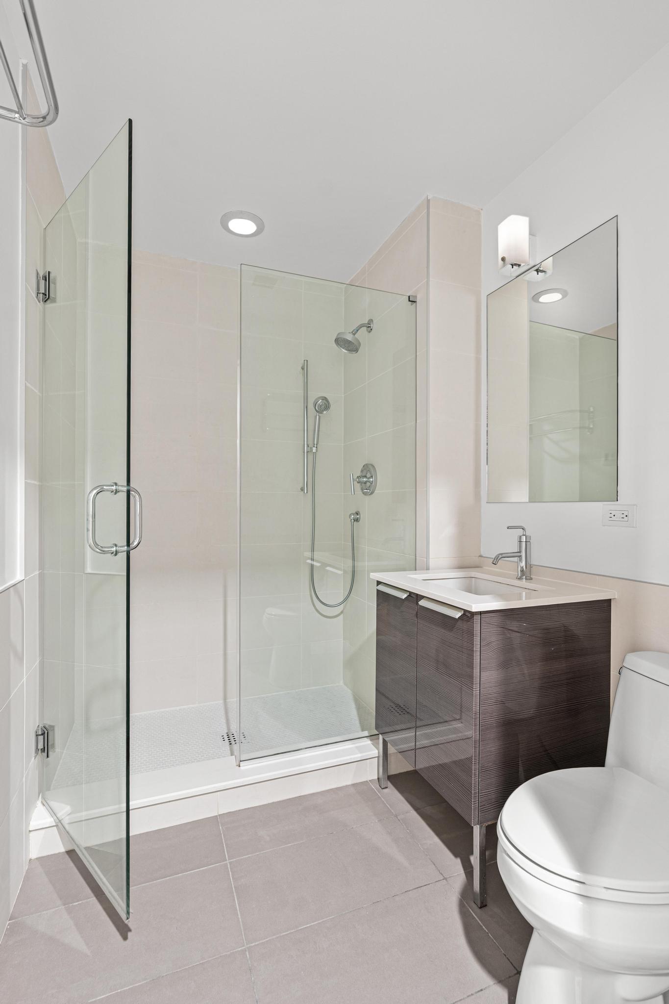 306 West 116th Street, Unit 1C Manhattan, NY 10026 - Photo 5 of 12 a bathroom with a granite countertop sink a toilet a mirror and shower