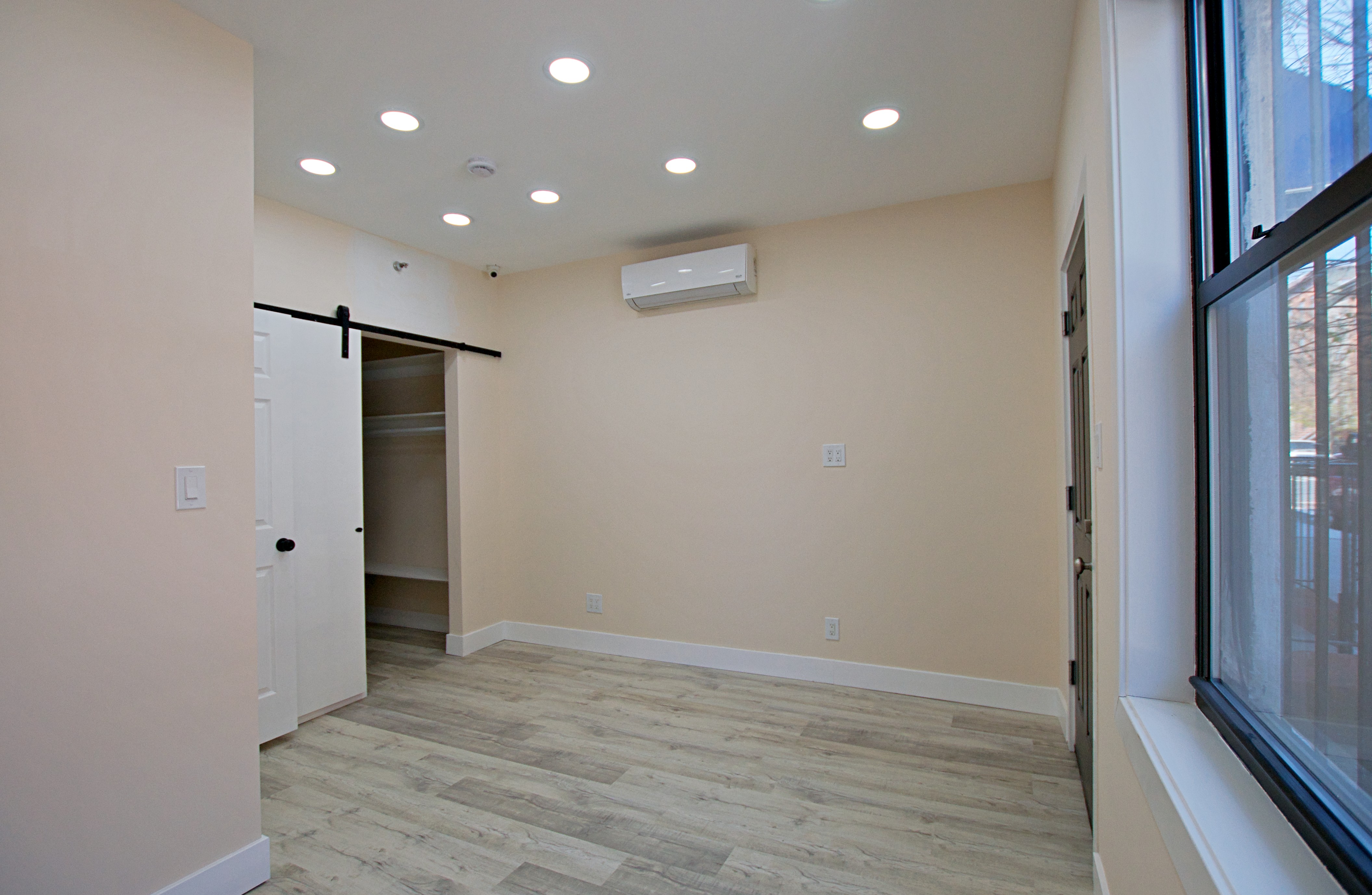 220 Madison Street, Unit 1A Brooklyn, NY 11216 - Photo 7 of 9 a view of an empty room with wooden floor and a window