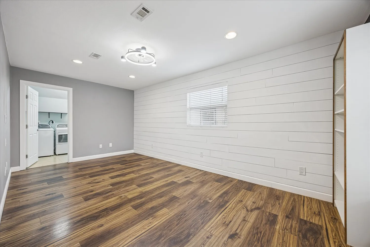 a view of an empty room with wooden floor and a window
