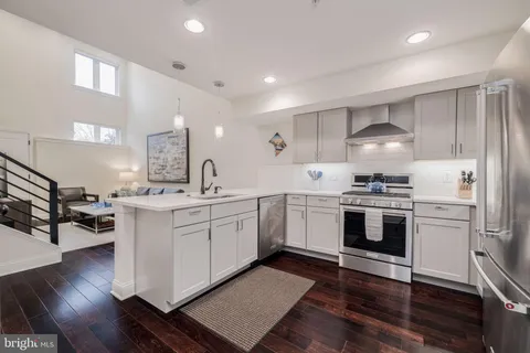 a kitchen with white cabinets stainless steel appliances and wooden floor