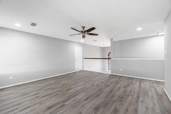 an empty room with wooden floor and ceiling fan