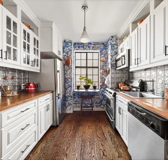 a kitchen with granite countertop a sink dishwasher stove and white cabinets with wooden floor
