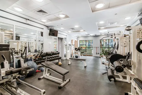 a room with gym equipment and wooden floor