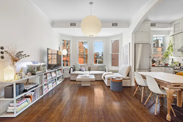 a large living room with stainless steel appliances furniture a rug and a large window