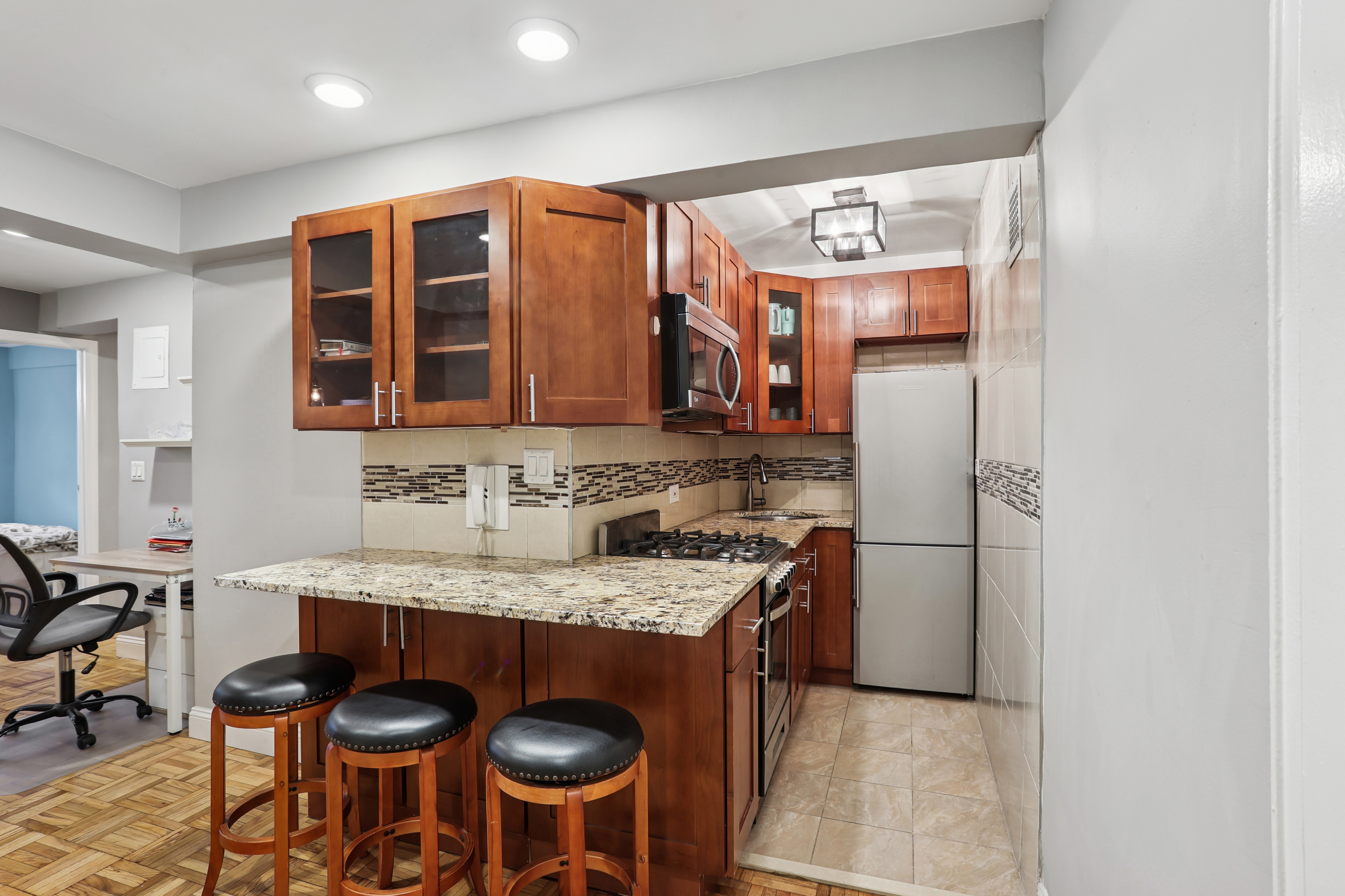 335 East 51st Street, Unit 4H Manhattan, NY 10022 - Photo 2 of 13 a kitchen with stainless steel appliances granite countertop a sink and a refrigerator